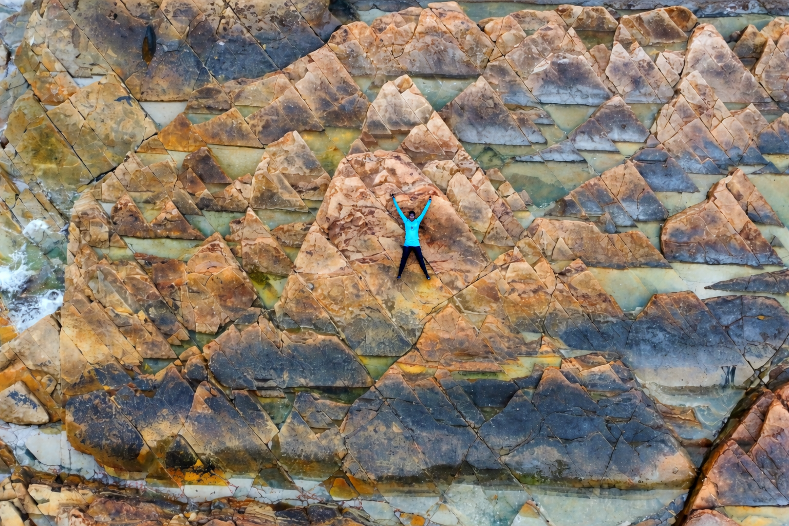 航拍東平洲更樓石六角岩層地貌，一名旅客在岩石上舉起雙手