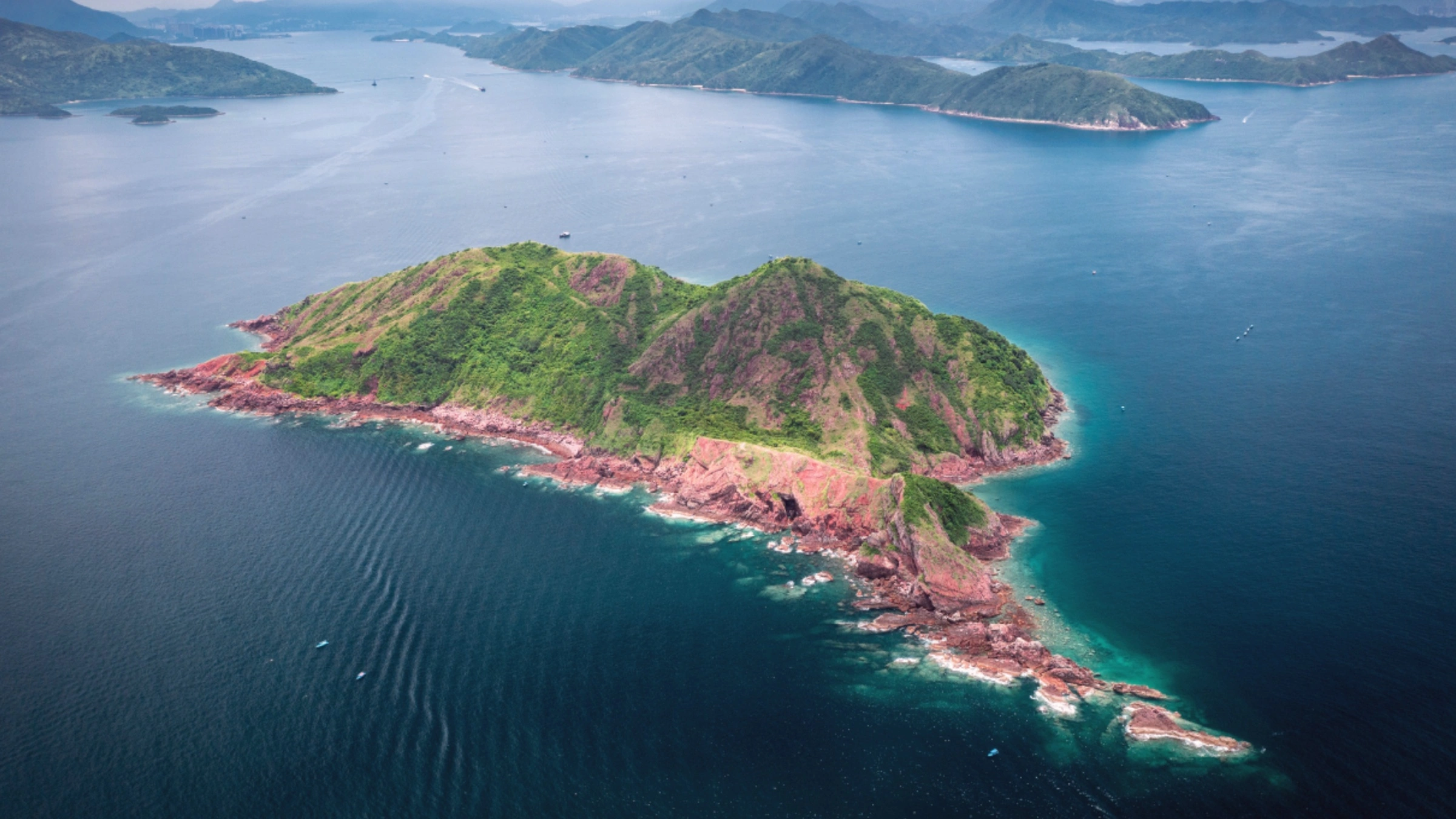 Aerial view of Port Island Hong Kong showing red sedimentary cliffs and turquoise coastline